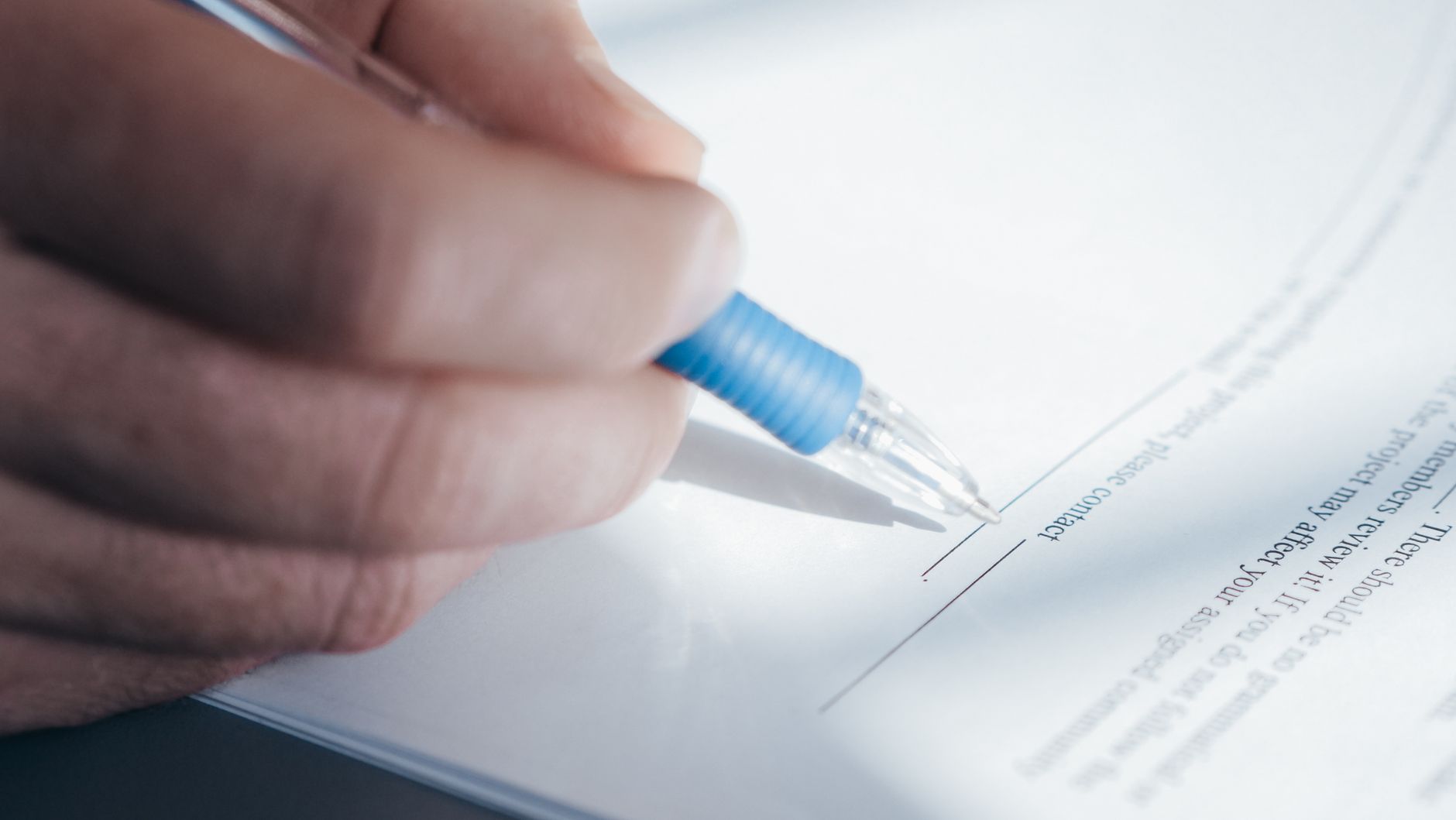 Persona firmando un documento legal con un bolígrafo