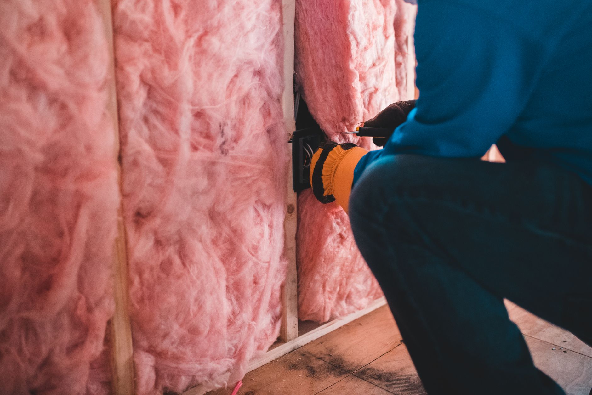 Contractor measuring insulation thickness in attic with ruler