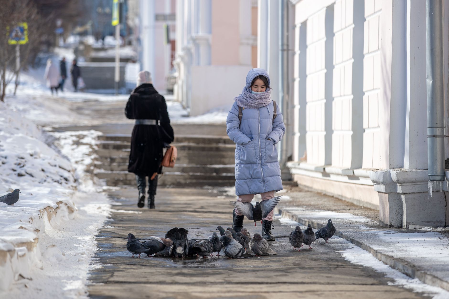 Person bundled in warm winter clothing walking through cold windy weather
