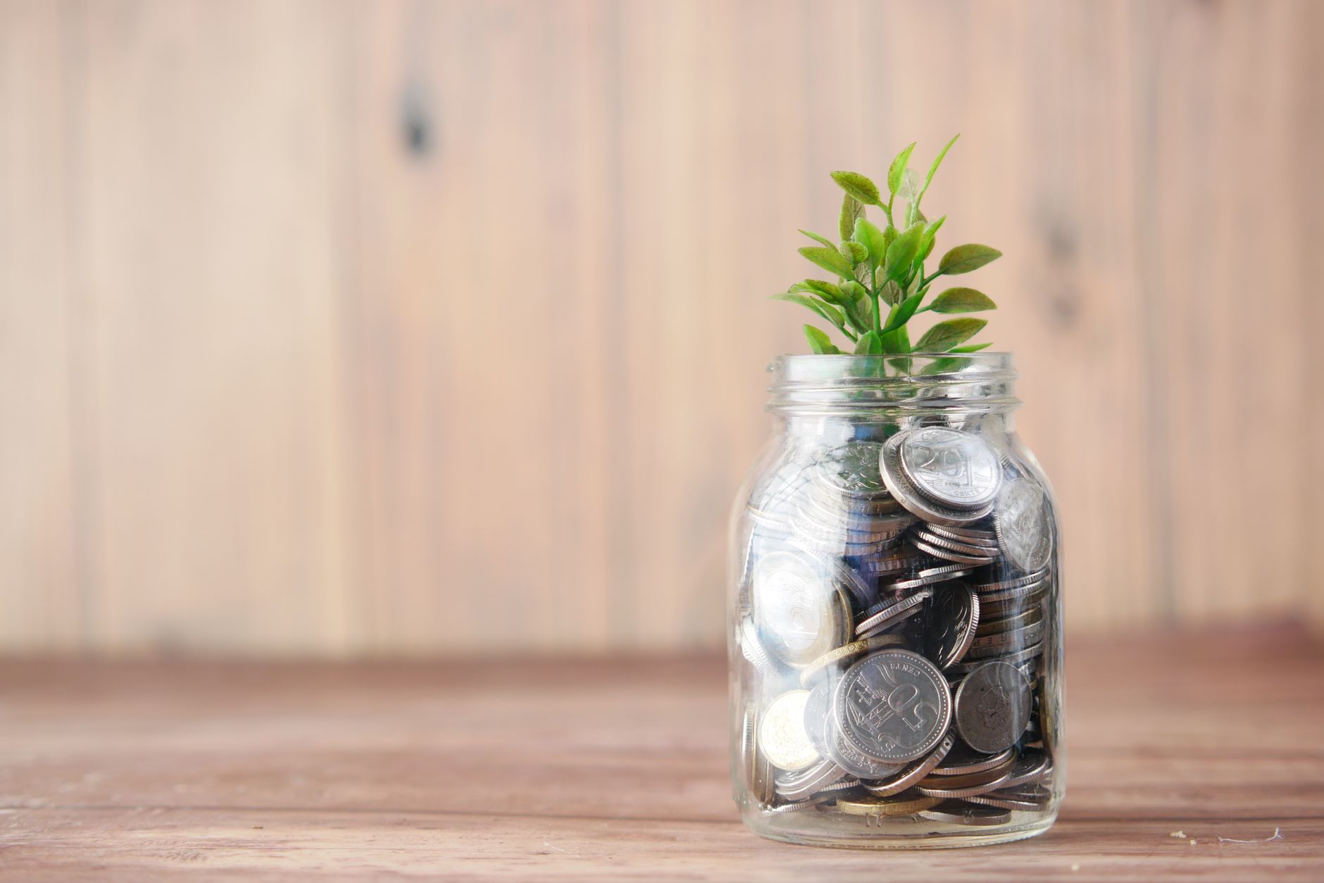 Coins and cash saved in a jar labeled for an emergency fund