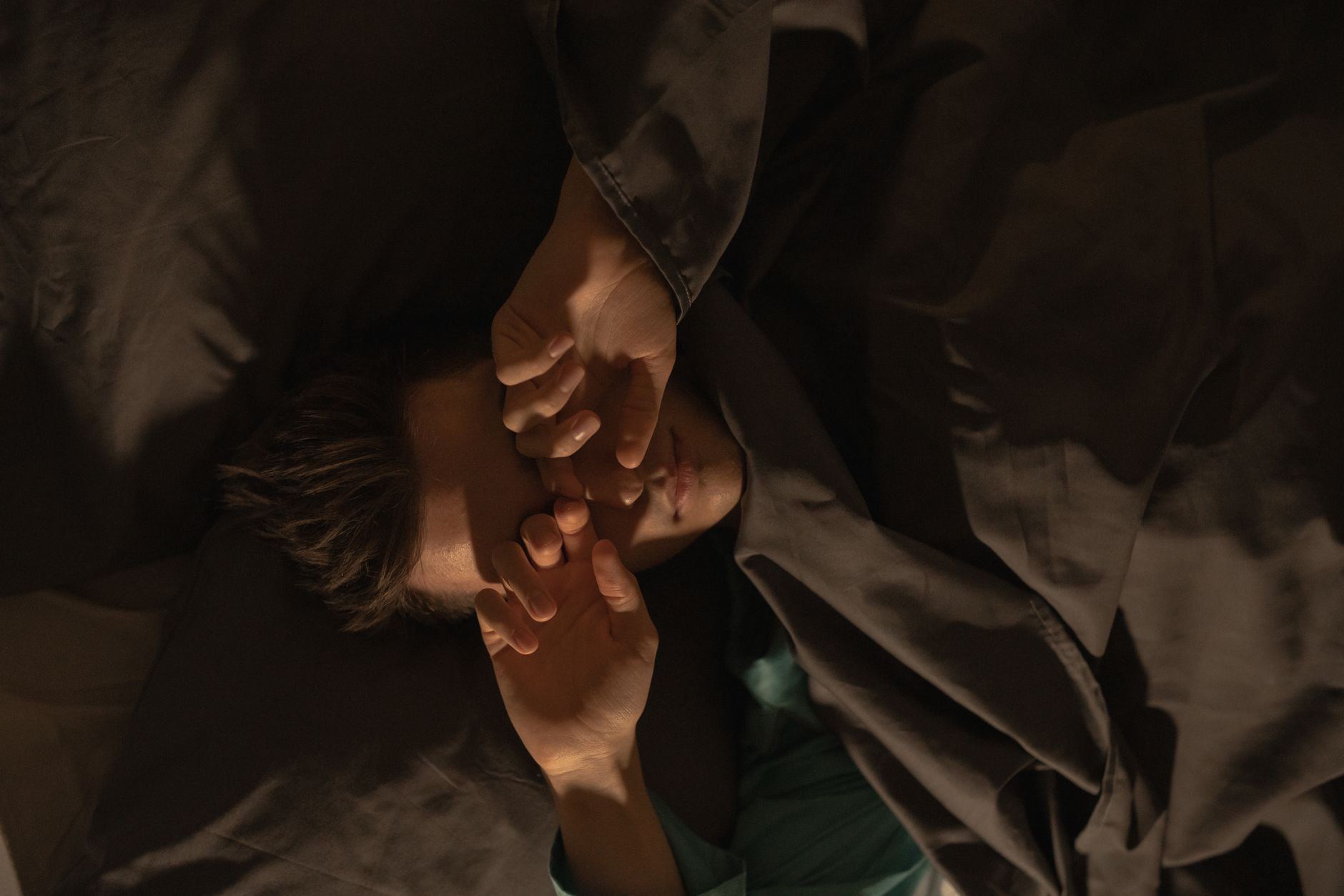 Person resting in bed — illustrating sleep debt and recovery