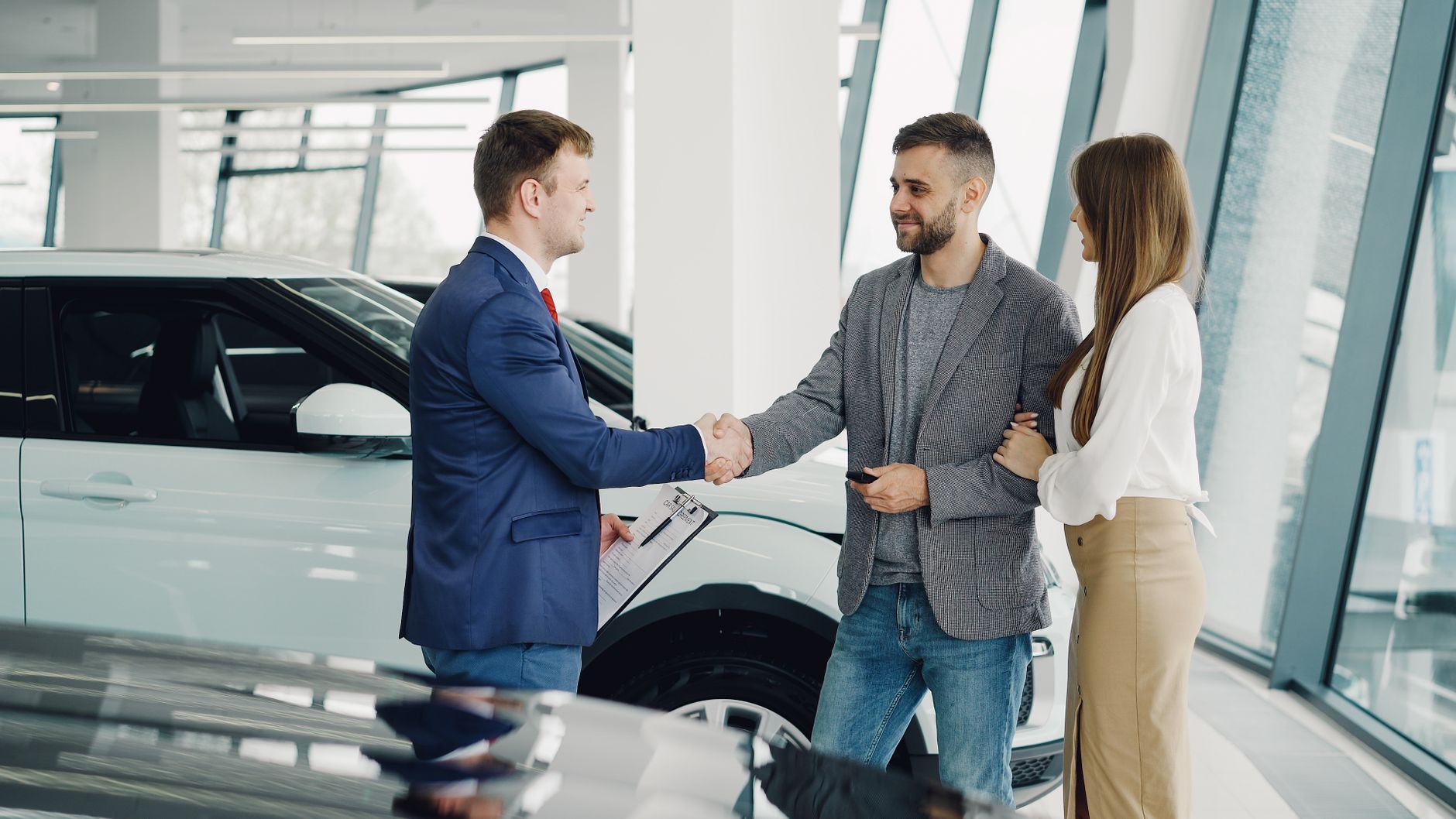 Family shaking hands with a car salesman after a purchase