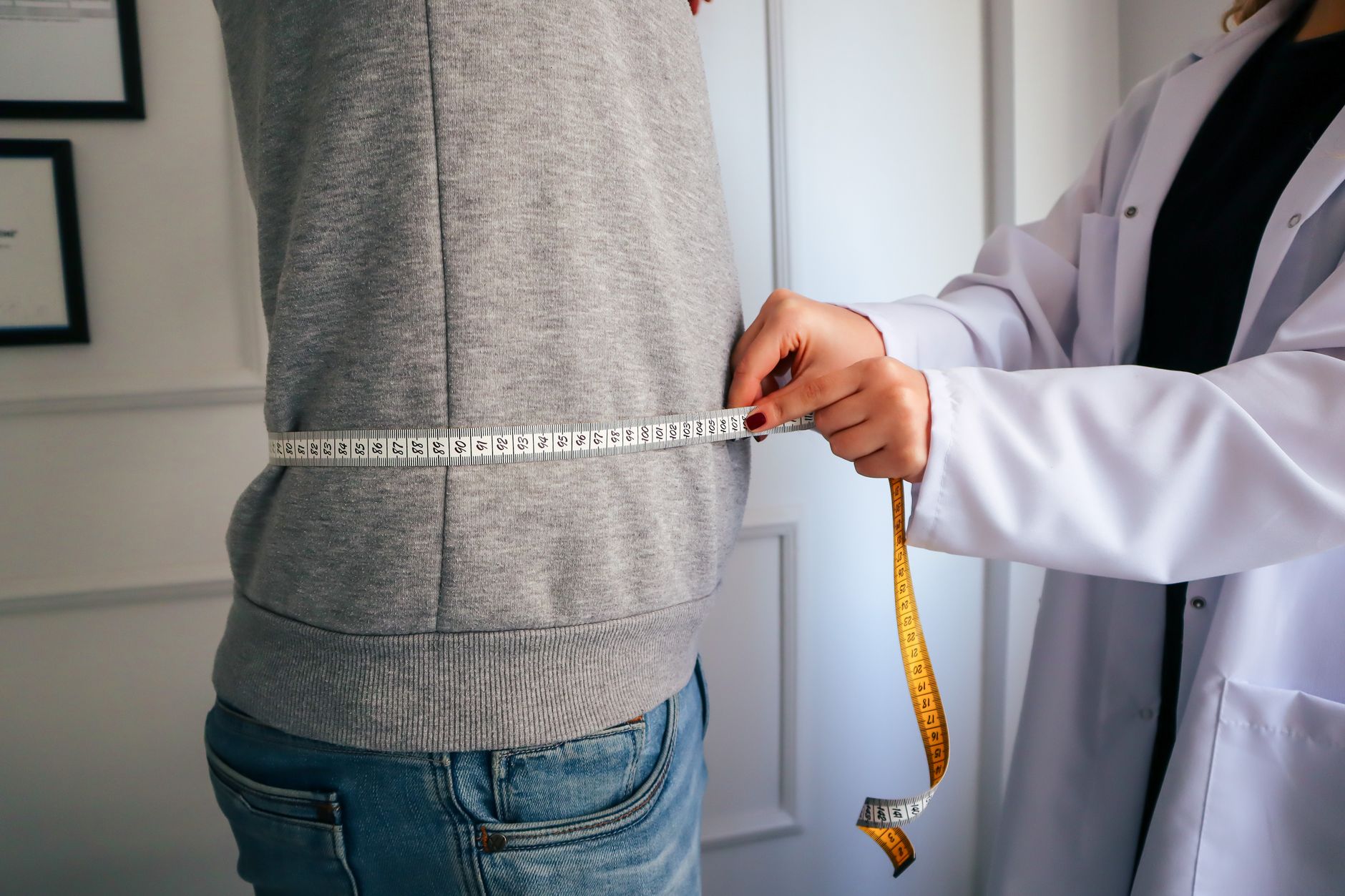 Nutritionist measuring a client's body composition with a tape measure