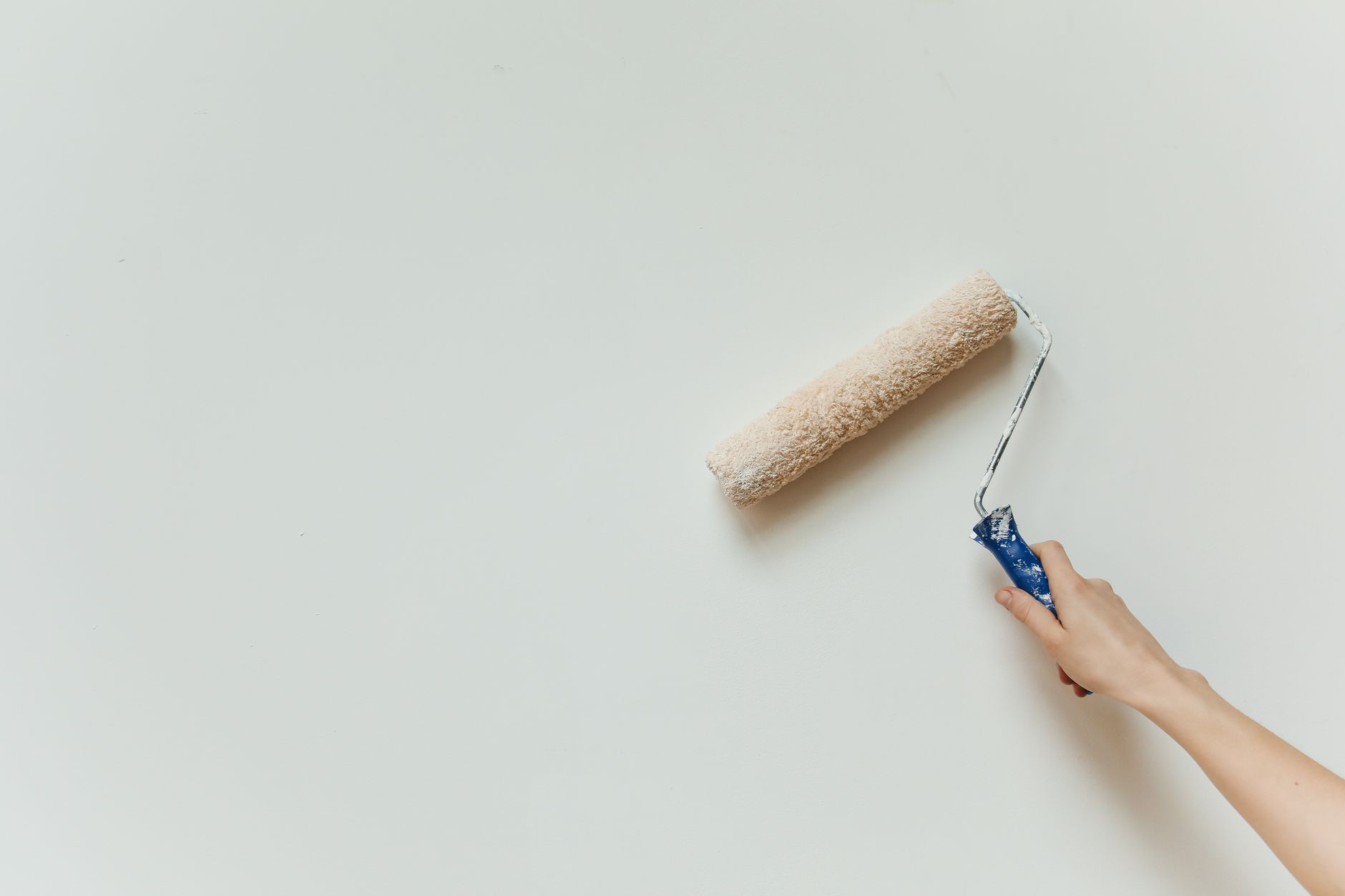 Person painting a wall with a roller — how much paint do I need