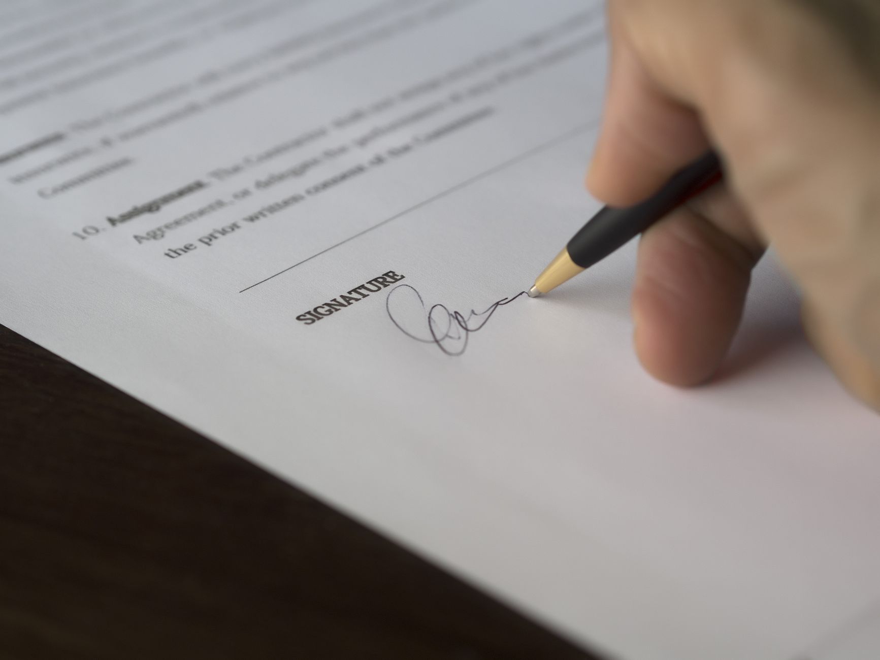 Person signing a legal document with a pen
