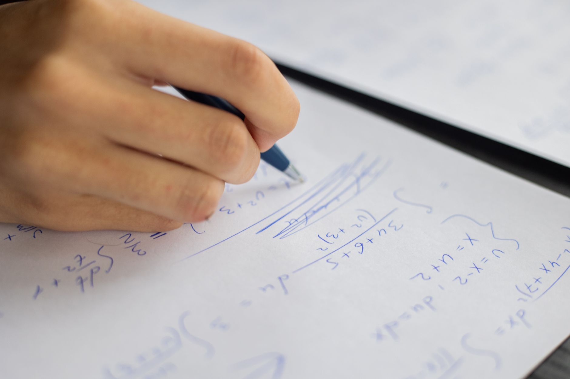 Student writing fraction math equations in a notebook